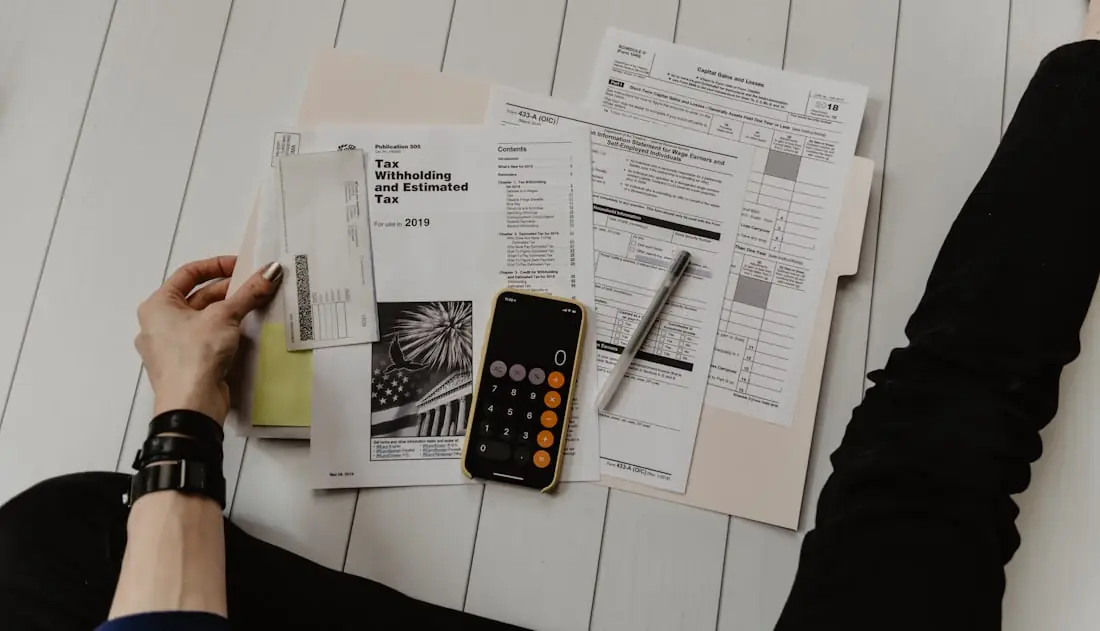 Documentos fiscais, calculadora e celular sobre a mesa, representando convênios e benefícios para empresas